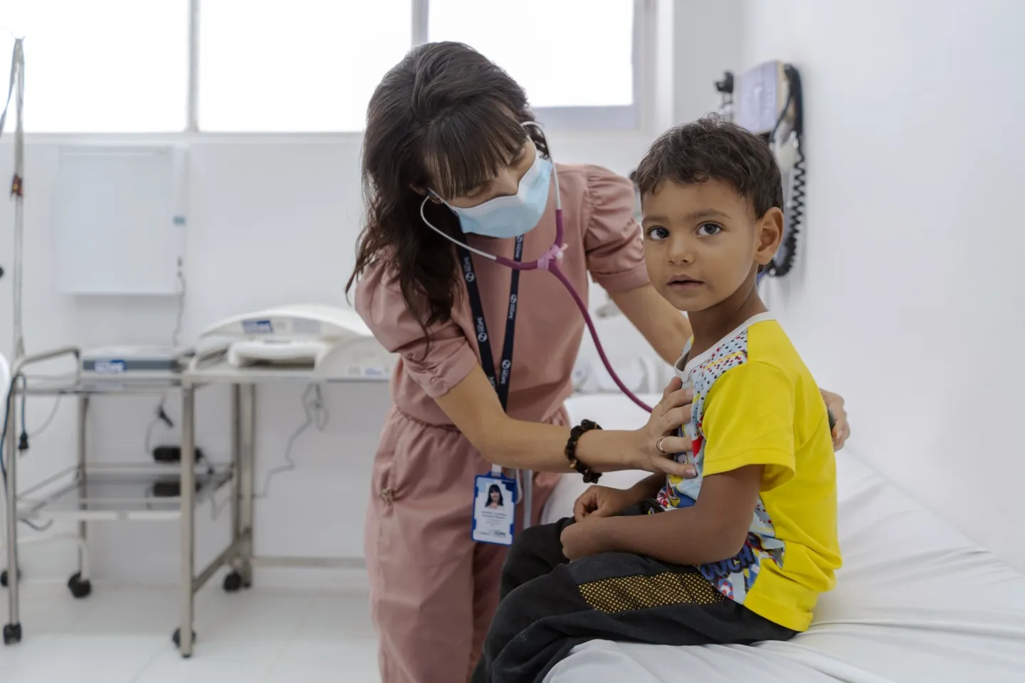 A medical staff member listens to the lungs of a young boy inside a clinic in Colombia