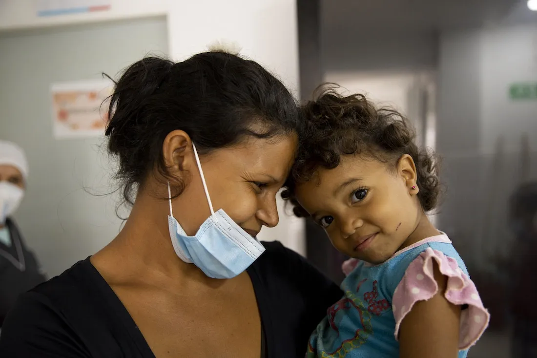 a woman and child close up. The woman is looking and smiling at the child while the child is looking at the camera